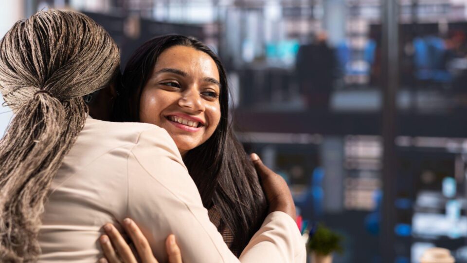 Esta imagem captura um momento de conexão emocional profunda e apoio mútuo entre duas mulheres em um ambiente profissional ou de saúde.