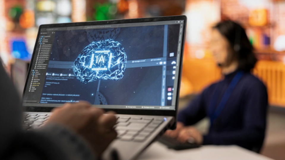 Esta imagem retrata o desenvolvimento de Inteligência Artificial em um ambiente de escritório moderno, focando na interface entre o humano e a máquina.