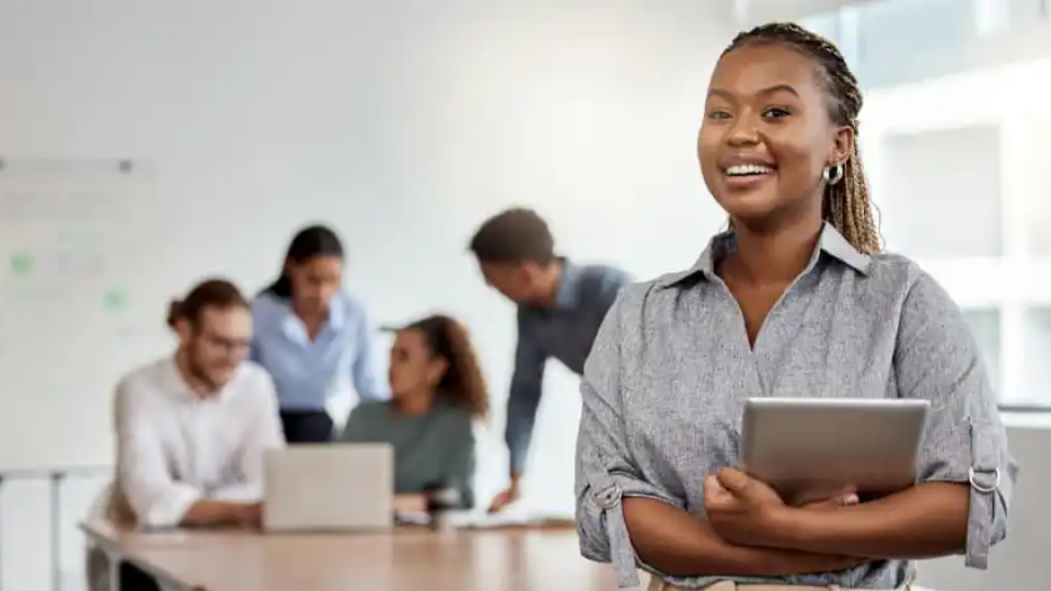 No centro e em foco, vemos uma mulher negra com um sorriso radiante e olhar confiante. Sua expressão transmite satisfação e clareza mental.