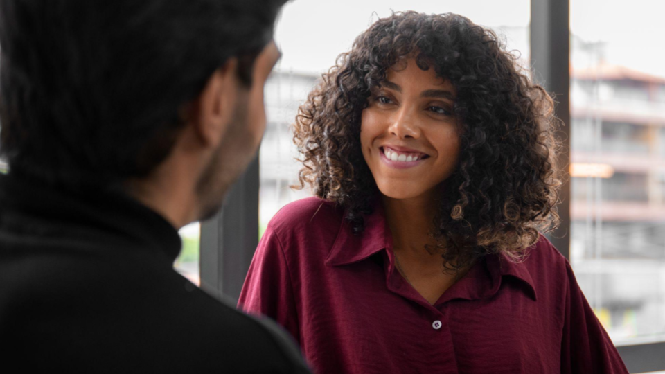 A imagem apresenta duas pessoas em uma interação próxima, com foco em uma mulher .