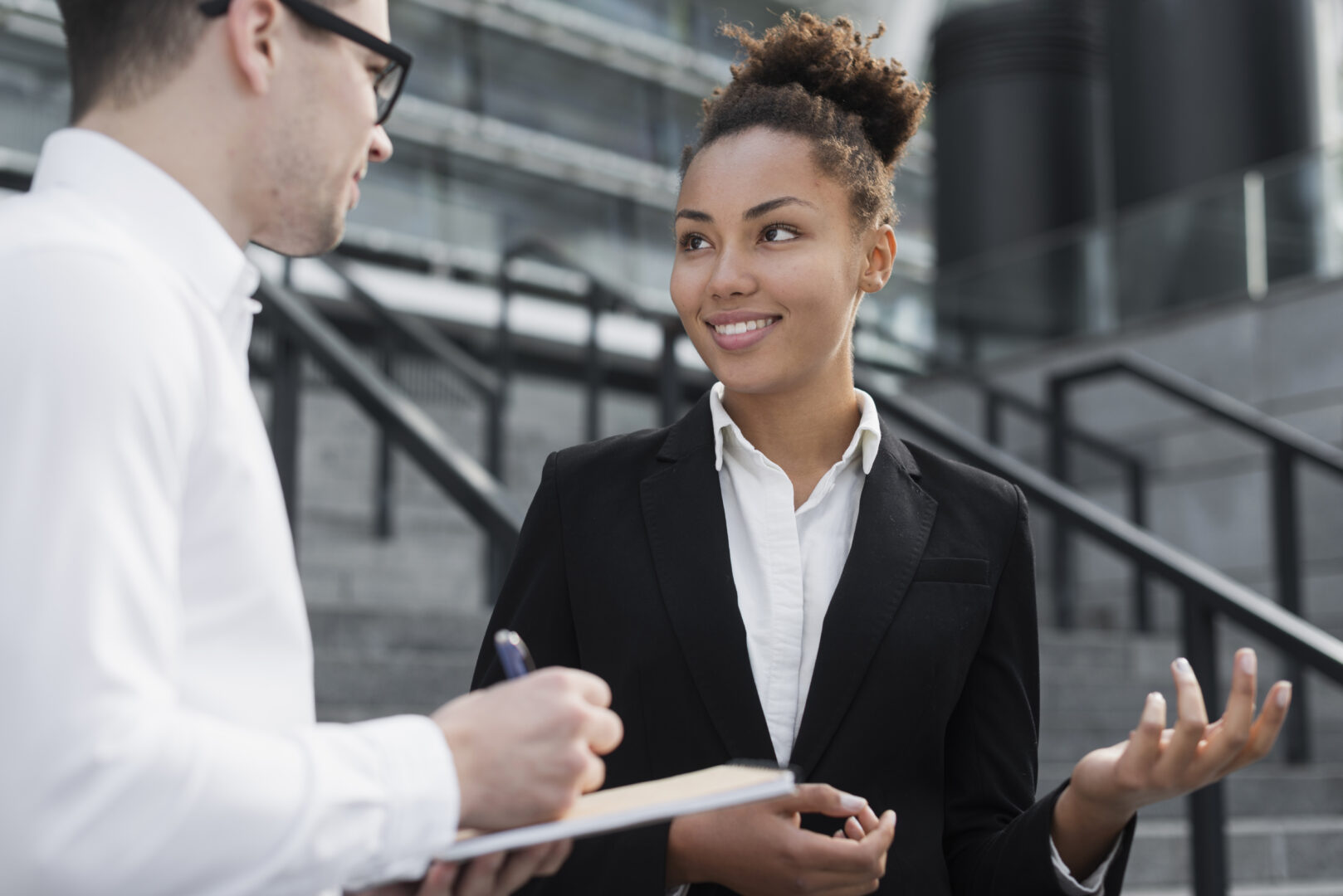 Esta imagem captura um momento de colaboração entre dois profissionais em um ambiente corporativo moderno e urbano.